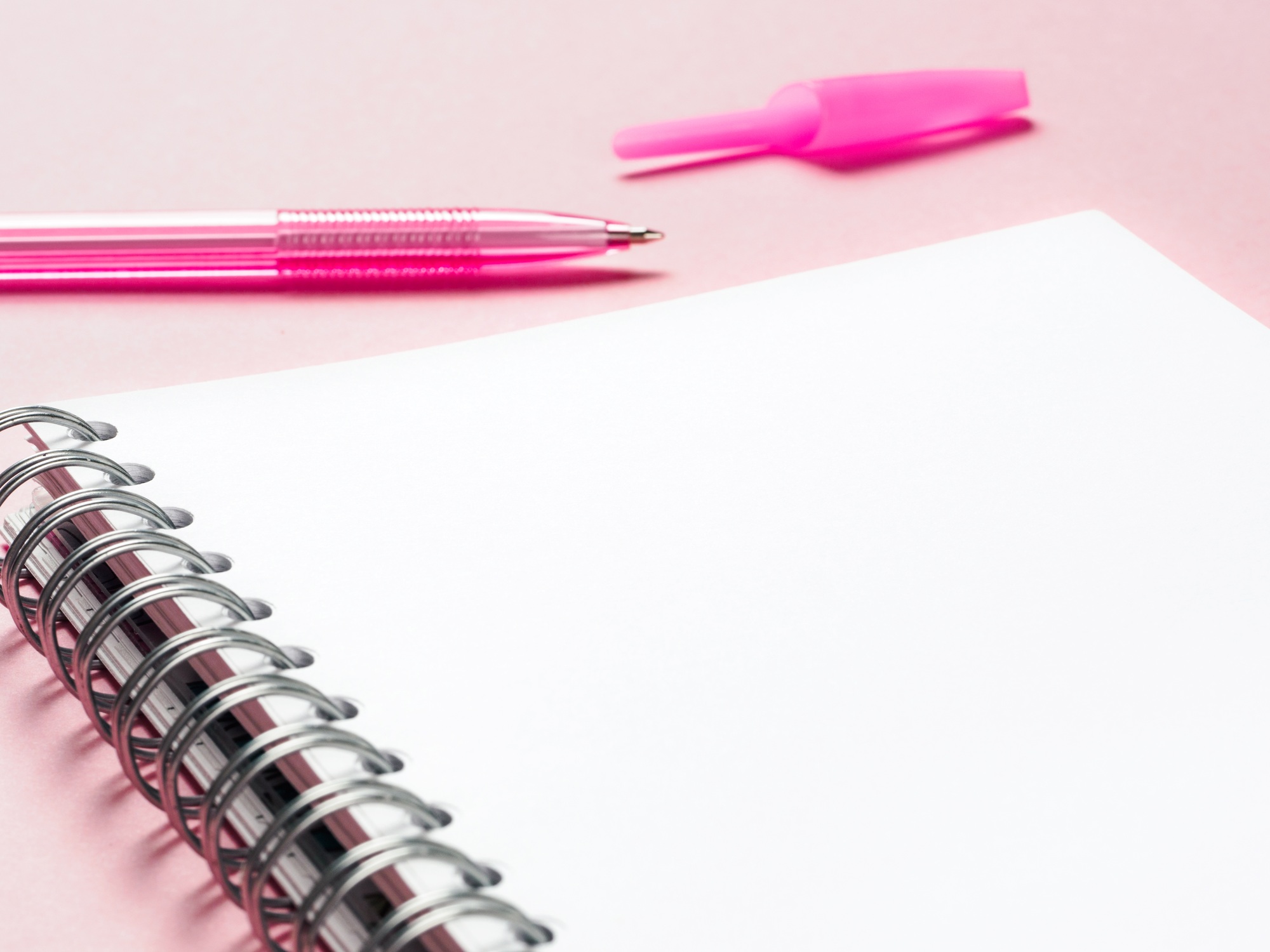 blank note with pen on pink background